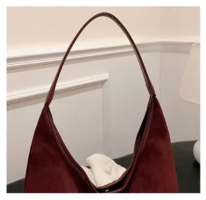 Close-up of burgundy suede hobo bag featuring contrasting white stitching and strap