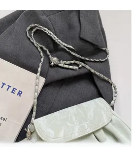 Vue détaillée du sac bandoulière plissé brillant avec chaîne en métal argenté sur veste