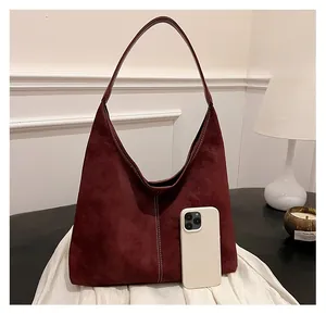 Detail of burgundy suede hobo bag showing large capacity with phone for scale