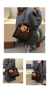 Detail view of leopard print shoulder bag with brown leather panel and plush dog charm
