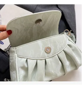 Détail du sac bandoulière plissé vert clair avec fermoir magnétique et pendentif en fourrure