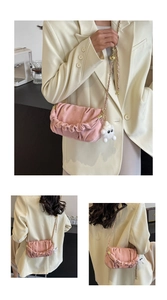 Detail of pink pleated crossbody bag with gold chain strap and fluffy monster charm