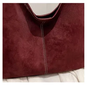 Detailed close-up of burgundy suede fabric with contrast stitching on a large tote bag