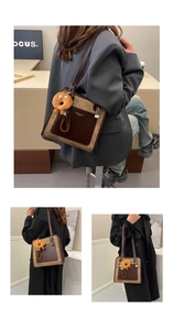 Close-up of a two-tone leather tote bag with a cartoon donut charm in an office setting
