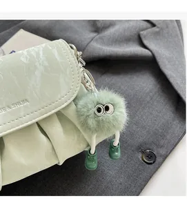 Détail du sac plissé vert sauge avec texture marbrée et charm monstre en peluche