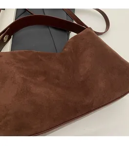 Macro detail of brown faux suede texture and gold round hardware on a shoulder bag