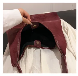 Macro shot of burgundy frosted leather bucket bag with magnetic closure and white stitching