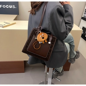 Detail of dark coffee leopard print tote bag with white stitching and plush charm