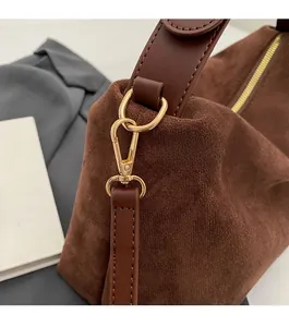 Detailed macro view of dark brown suede bag texture with elegant gold hardware and leather strap