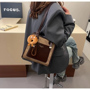 Side view of a vintage contrast-color tote bag featuring a plush donut charm and brand logo