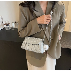 Détail du sac bandoulière plissé gris clair avec chaîne argentée et breloque sur mannequin