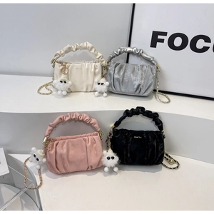 Detail of trendy pleated shoulder bags in cream, silver, pink, and black with cute charms