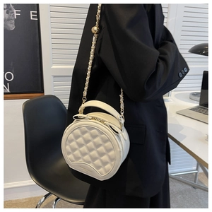 Détail du petit sac rond matelassé blanc avec chaîne dorée et fermetures éclair à nœud