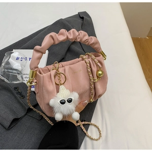 Detail of pink ruched handbag with golden chain and cute plush keychain accessory