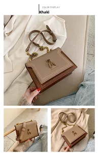 Close-up of khaki leather bag featuring gold insect emblem and chain shoulder strap
