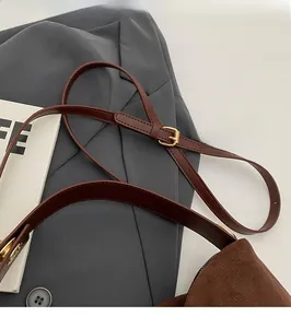 Detail of the adjustable brown leather shoulder strap with a golden metal buckle