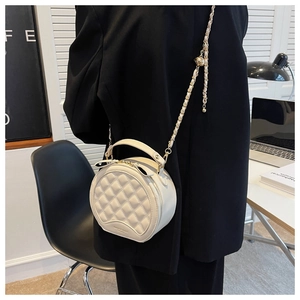 Détail du petit sac rond matelassé blanc avec chaîne dorée et boucle sphérique