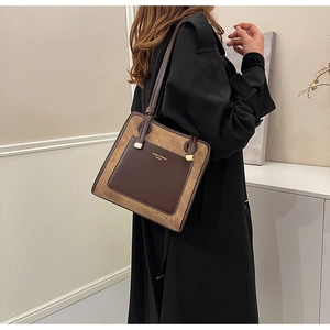 Detail of a brown and khaki suede tote bag showing the side view and thin shoulder strap