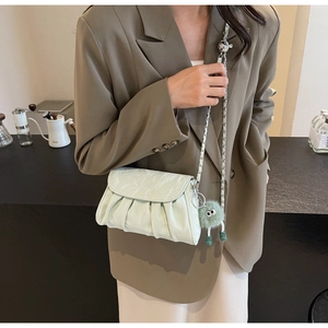 Détail du sac bandoulière plissé vert menthe avec bandoulière chaîne et gris-gris peluche