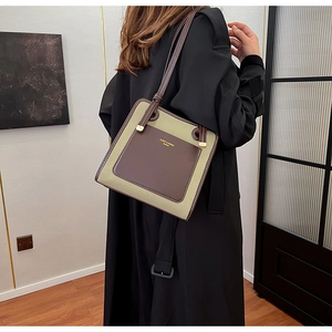 Detail of canvas and brown leather tote bag showing metallic rings and logo