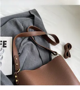 Close-up of brown litchi grain leather tote bag with gold rivets and spare strap