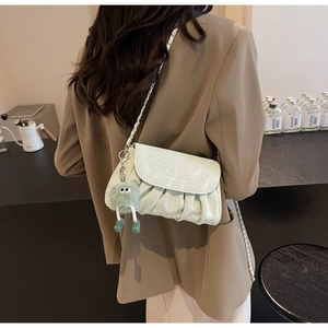 Détail du sac bandoulière plissé vert clair avec chaîne et breloque monstre en peluche