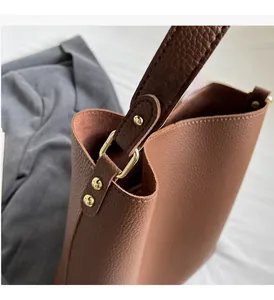 Detail of premium brown pebble leather tote with golden D-ring hardware and rivets