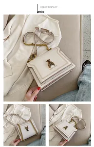 Close-up of golden bee buckle and metal rivets on white leather crossbody bag
