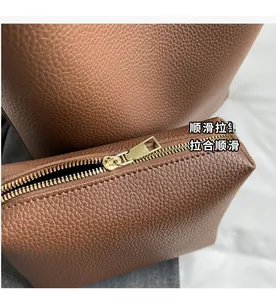 Close-up of smooth gold zipper and brown lychee grain texture on a tote bag detail