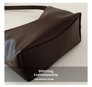 Close-up of fine stitching and dark brown PU leather texture on a tote bag