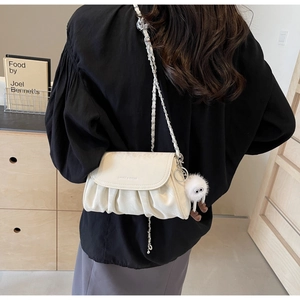 Détail du sac bandoulière plissé crème avec chaîne argentée et breloque en peluche