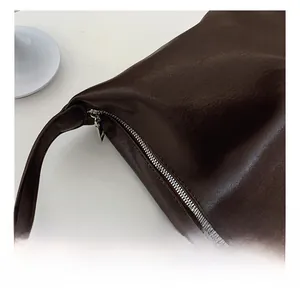 Detailed macro view of the silver metal zipper and brown lychee grain leather texture