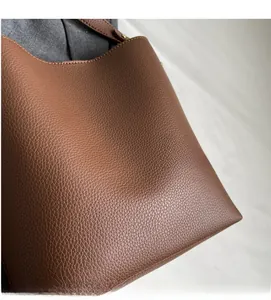 Close-up of brown litchi pattern leather bucket bag with fine stitching and metal hardware