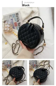 Détail du sac rond noir matelassé avec bandoulière en chaîne dorée et poignée