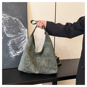 Detail of dark green suede hobo bag featuring vertical stitching and soft texture