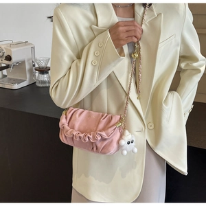 Detail of pink pleated cloud bag with gold chain strap and cute white plush monster charm