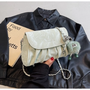 Détail du sac plissé vert menthe avec chaîne argentée et breloque monstre en peluche