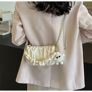 Detail of off-white pleated cloud bag with gold chain and cute fur ball pendant