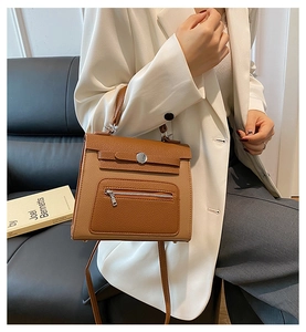 Detail of brown leather handbag with silver round buckle and functional front zipper pocket