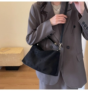 Model wearing black suede Boston bag with gray suit to show size and texture