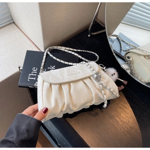 Détail d'un sac à bandoulière plissé beige avec chaîne et pompon décoratif doux