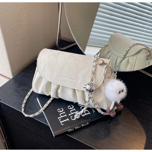 Vue détaillée du sac plissé blanc crème avec chaîne dorée et breloque en peluche