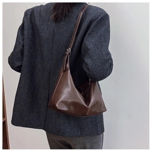 Detail of a dark brown faux leather hobo bag with adjustable strap and silver buckle