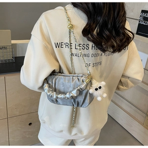 Detail of silver pleated cloud bag with gold chain strap and plush sunglasses charm
