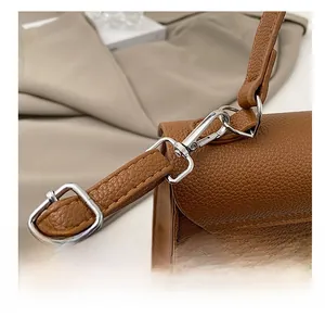 Detail of silver hardware hook on brown lychee grain leather handbag with fine stitching