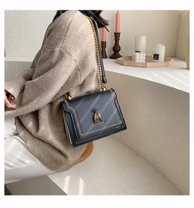 Detail of vintage gold bee buckle and woven stitching on a black leather square bag