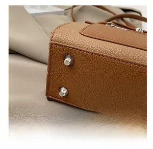 Detail of metal feet studs on brown lychee grain leather handbag base for protection