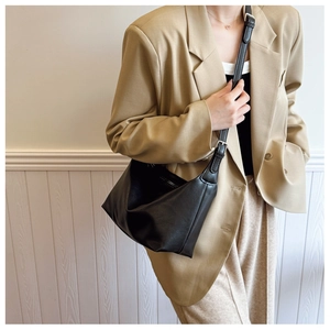 Detail of a minimalist black hobo bag with a fine leather texture and silver buckle