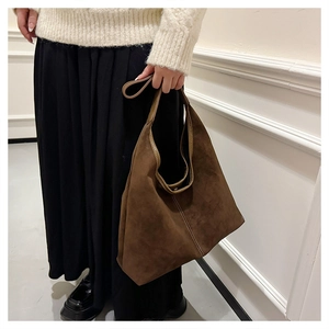 Detail of retro brown suede hobo bag with contrast stitching held by a model
