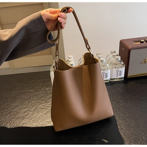 Detail view of large dark brown lychee textured leather bucket bag with shoulder strap